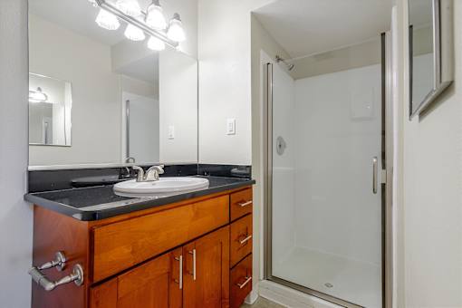 A bathroom with a sink, mirror, and shower.