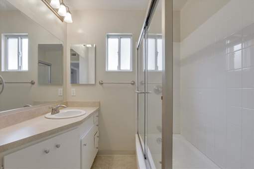 A bathroom with a sink, mirror, and shower.