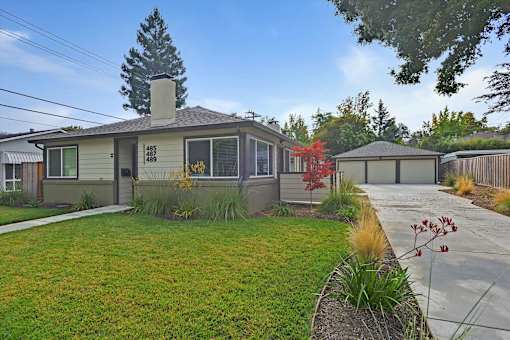 A house with a green lawn and a tree in the front yard.