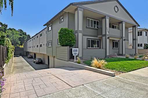 A residential building with a grey facade and a green lawn in front.