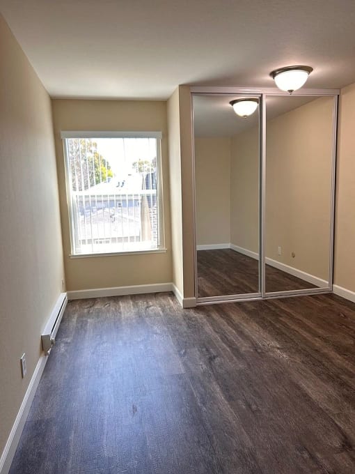 an empty living room with a large window and wooden floors