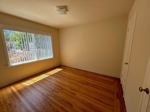 an empty room with a large window and wooden floors