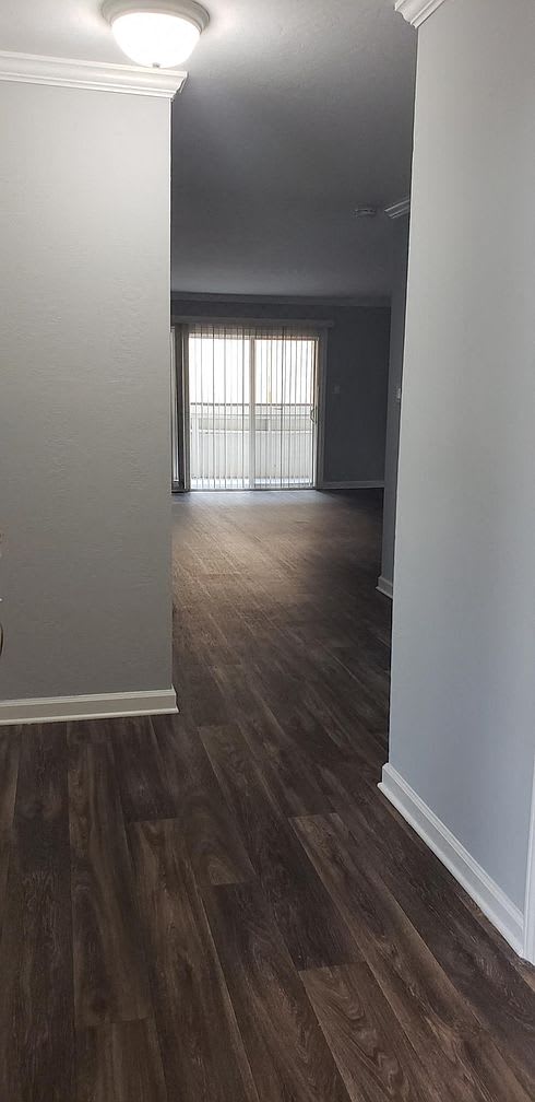 A room with wooden flooring and a window with blinds.