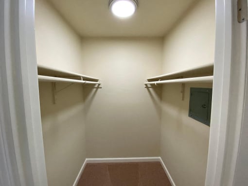 a walk in closet with white walls and a ceiling light