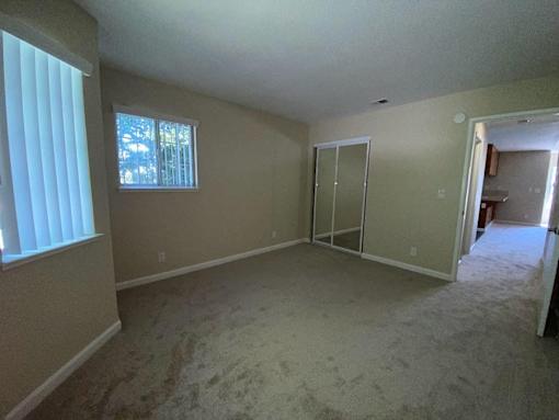 A room with a carpeted floor and a window with blinds.