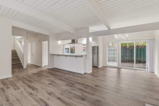 A spacious room with wooden floors and white walls.
