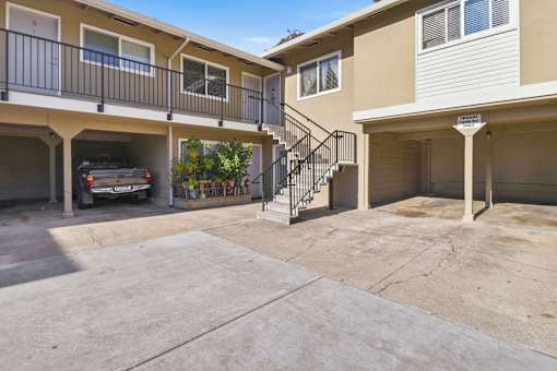 A car is parked in the garage of a two-story apartment building.