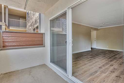 A room with a sliding glass door and wooden flooring.