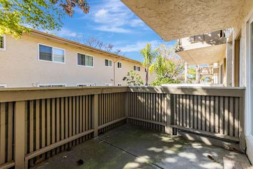 A balcony with a wooden railing and a concrete floor.