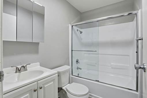 A white bathroom with a toilet, sink, and shower.