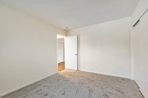 A room with a carpeted floor and a doorway leading to another room.