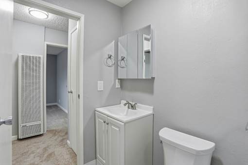 A white bathroom with a toilet, sink, and mirror.