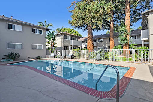 A swimming pool in a residential area with a red and white striped pool edge.