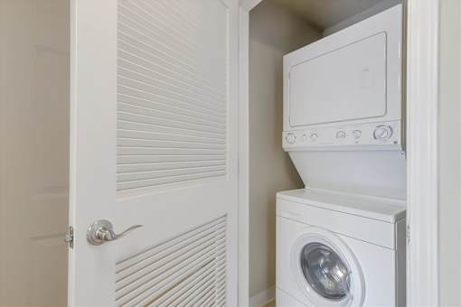 A white washing machine is in a small white closet.