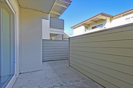 A view of a building with a grey wall and a white door.