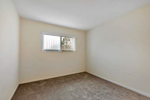 A room with a window and carpeted floor.
