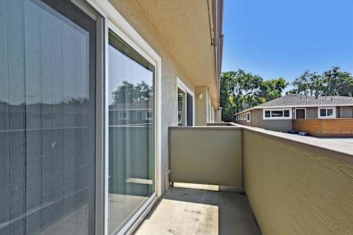 A balcony with a glass door and a screen door.