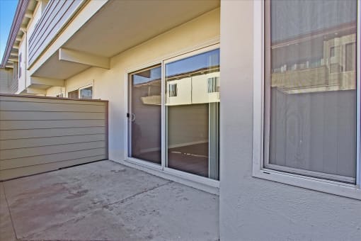 A patio with a sliding glass door and a concrete floor.