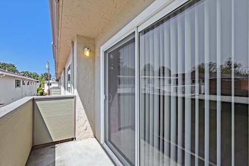 A balcony with a glass door and a concrete floor.