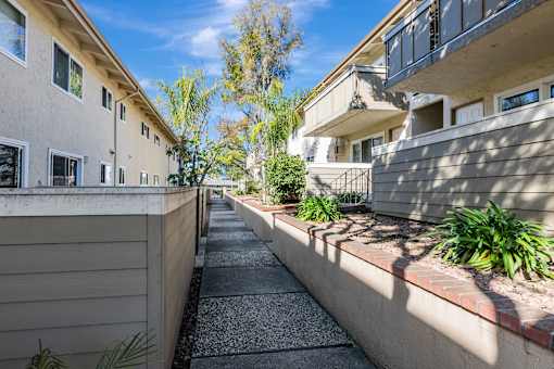 A sunny day in a residential area with apartment buildings and a sidewalk.