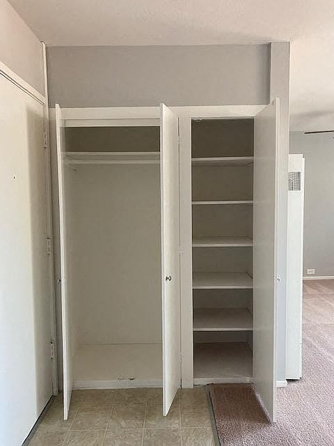 A white closet with shelves and a mat on the floor.