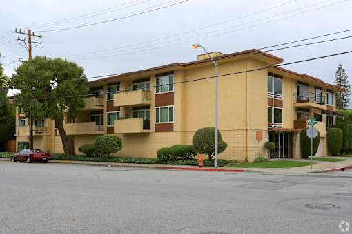an apartment building on a street corner with a red car