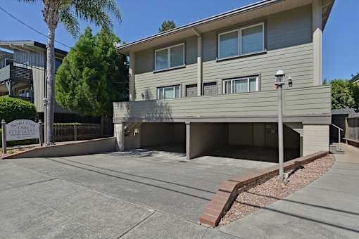 A two-story residential building with a parking area in front.