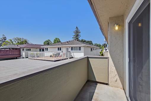 A balcony with a view of a house and trees.
