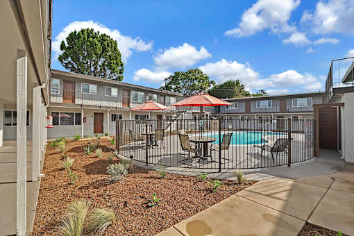 A pool surrounded by a fence and chairs.