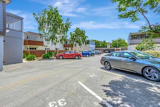 A parking lot with cars and a building in the background.