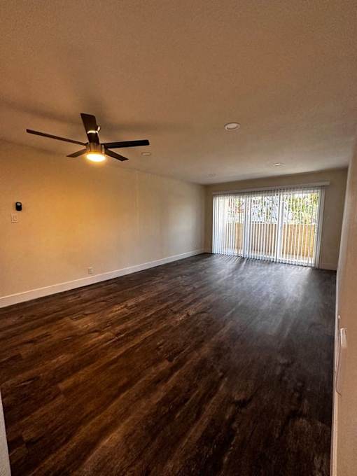 an empty living room with a ceiling fan