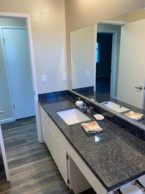 A bathroom with a granite counter top and a white vanity.