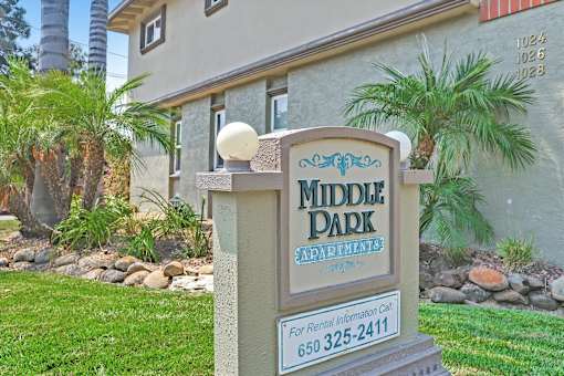 A sign for Middle Park Apartments stands in front of a building.