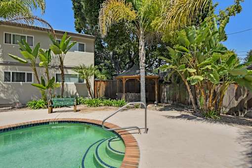 A pool surrounded by a concrete patio and a wooden deck.