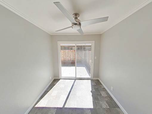 A room with a ceiling fan and a door leading outside.