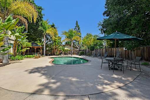 A backyard with a pool and a table set up for dining.