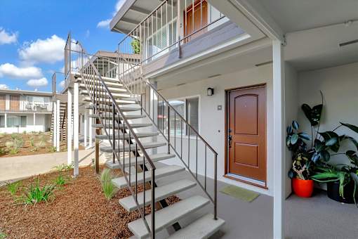 A staircase with a metal railing leads up to a balcony.