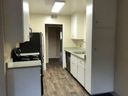 A kitchen with white cabinets and a black fridge.