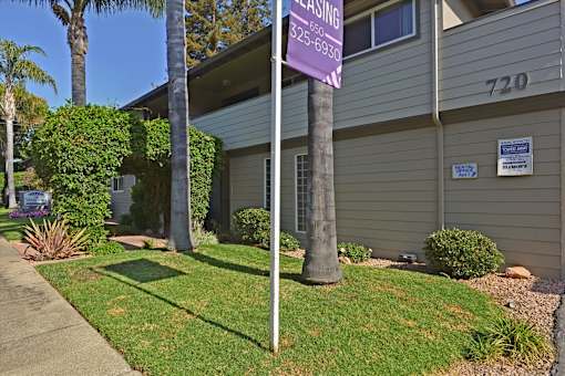 A leasing sign is posted on a pole in front of a house.