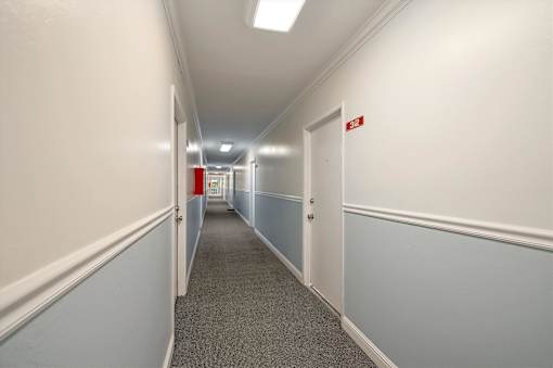 A long hallway with a red exit sign on the wall.