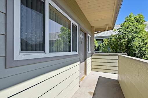 A balcony with a wooden floor and a window with a white frame.