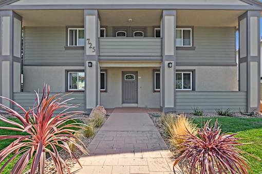 The image shows a modern two-story house with a grey exterior and a balcony on the second floor.