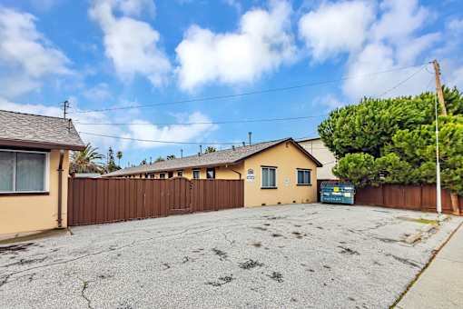 A house with a brown fence and a blue car in front.