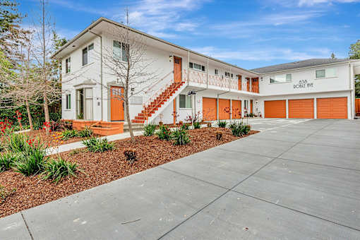 A white building with orange stairs and a red door.
