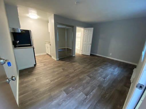 a empty living room with wood flooring and a kitchen