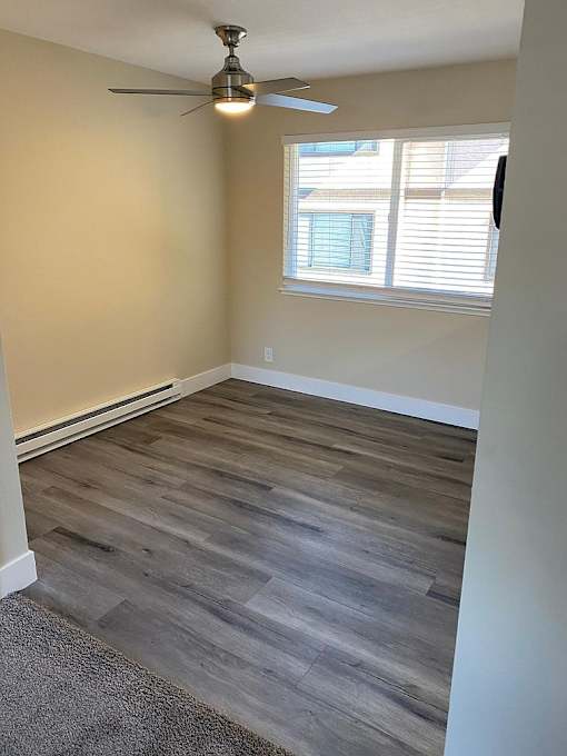 A room with a ceiling fan and a window with blinds.