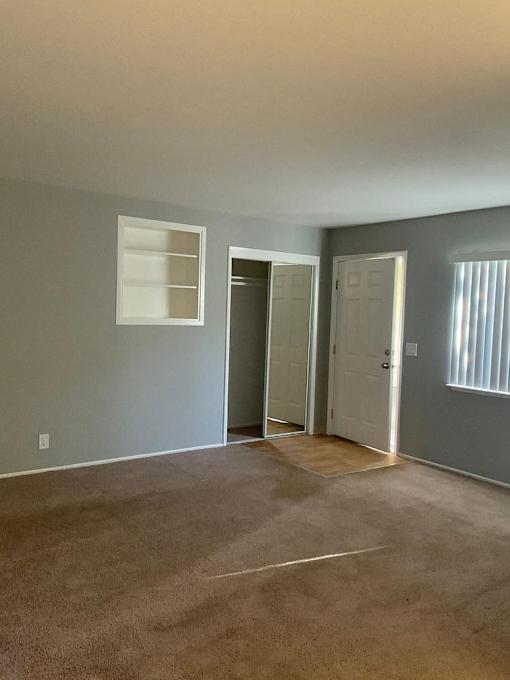 A room with a carpeted floor and a white door.