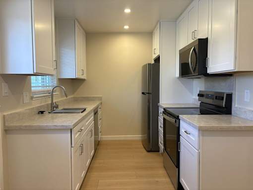 A kitchen with white cabinets and appliances.