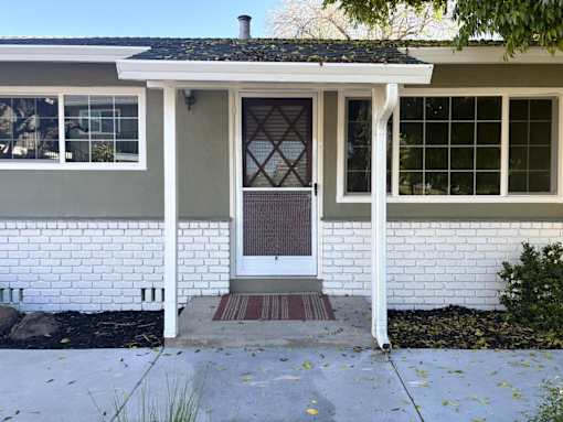 A white house with a brown door and a small porch.