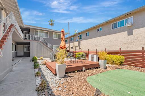 A sunny day at a residential area with a building, a patio, and a green lawn.